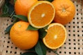 Orange fruit pile and two halves slice with green leaves fruits or vegetables on wicker tray closeup. Royalty Free Stock Photo