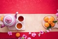 Orange fruit, Pink cherry blossom and teapot with Copy space for text on red texture background, Chinese new year background Royalty Free Stock Photo