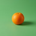 Orange fruit with a textured surface on a plain green background. The orange is Royalty Free Stock Photo