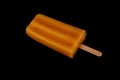 Orange fruity yogurt on a stick popsicle isolated on isolated on black