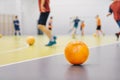 Orange Futsal Soccer Ball on Indoor Training Pitch. Young Players On Sports Practice Running Balls in Blurred Background Royalty Free Stock Photo