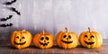 Orange ghost pumpkins with bats on gray wooden board background. halloween decoration concept