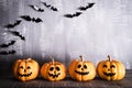 Orange ghost pumpkins with witch hat on gray wooden board background with bat. halloween concept