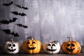 Orange ghost pumpkins with witch hat on gray wooden board background with bat. halloween concept