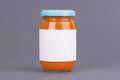 Orange glass jar for baby food bank on grey background. Organic baby food puree. Mock up without template design label. Royalty Free Stock Photo
