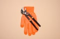 Orange glove and metal universal adjustable wrench on a beige background
