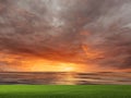 Orange gold sunset at sea  reflection on water wave ,dramatic fluffy clouds at evening sky  and green grass on field  nature lands Royalty Free Stock Photo