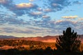 Orange golden hour sunshine on the foothills of the Rock Mountains in Colorado Springs USA with puffy clouds framed by shadowy Royalty Free Stock Photo