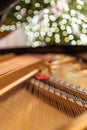 The grand piano interior with visible strings In the background a blurred Christmas tree, ornaments and lights Royalty Free Stock Photo