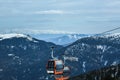 Orange gondola cabins of cableway lift on winter snowy mountains background beautiful scenery