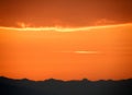 Orange gradation of sunset cloudy sky over the silhouette of mountain range Royalty Free Stock Photo