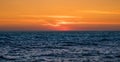 Orange gradient sky at dusk over ocean, just after sunset with dark waves below. Royalty Free Stock Photo