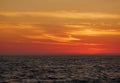 Orange gradient sky at dusk over ocean, just after sunset with dark waves below. Royalty Free Stock Photo