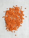 Orange grains of lentils scattered on a white background. Abstract wallpaper.