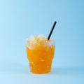 Orange Granizado in disposable plastic cup on blue background. Refreshing summer iced drink. Sweet Shaved ice. Slushie fruit drink Royalty Free Stock Photo