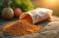 Orange granules spill from clear bag onto rustic wood table. Pineapple and egg visible in soft focus background. Sunlight streams Royalty Free Stock Photo