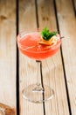 Orange grapefruit daiquiri cocktail with mint in a unique serving on a wooden background with lines