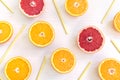 Orange and grapefruit slices with yellow straws lying on a light background