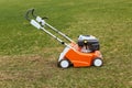 Orange grasscutter standing on ground on green grass, special equipment for trimming grass, grass-mower oudoor