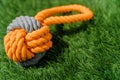 Orange gray rope dog toy on synthetic grass hard light