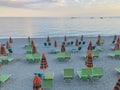 Orange and green beach chairs and umbrellas by the sea across sunset sky. Summer vacation. Travel Royalty Free Stock Photo