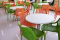 Orange and green chairs around white tables. A modern interior of food court in a mall, cafe, airport or family fast food Royalty Free Stock Photo