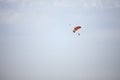 Orange and Green parachute, made for two persons, a beginner and an instructor, falling fro the sky during a parachuting skydiving