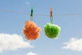 orange and green shower sponges hanging from colored clothespins drying in the open air with a blue sky and white clouds Royalty Free Stock Photo