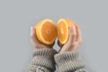 Orange half cut 2 pieces on women hands with sweater on light grey background. horizontal image