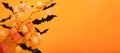 Orange Halloween background. Flock of black bats and branch of dry orange flowersfor Halloween. Black paper bat silhouettes on