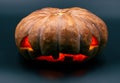 Orange Halloween pumpkin on black background. Halloween party decor. Carved pumpkin with scary face and orange glow. Royalty Free Stock Photo