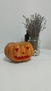 an orange Halloween pumpkin with a sinister smile and a couple of objects in the background