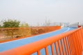 Orange handrails of blue footbridge in sunny hazy winter afternoon