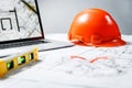 Orange hard hat, laptop  with drawings, level meter and protective glasses lying in a  blueprints on a table Royalty Free Stock Photo