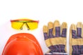 Orange hard hat, leather work gloves and safety glasses on a white background. Copy space. Royalty Free Stock Photo