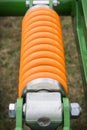 Orange hard spring made of steel. Part of big industrial or agricultural machine Royalty Free Stock Photo