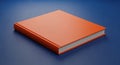 Orange Hardcover Book Lying on a Blue Surface Royalty Free Stock Photo