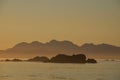 Mountains of Brookes Peninsula silhouetted by setting sun with reef in front and orange haze