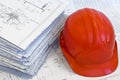 Orange helmet and heap of project drawings Royalty Free Stock Photo