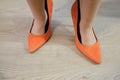 Orange hiccups woman shoes on a tiny baby girl feet