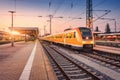 Orange high speed train on the railway station at sunset