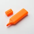 An orange highlighter marker with the cap removed rests on a white surface. The Royalty Free Stock Photo