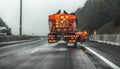 Orange highway maintenance gritter truck spreading de-icing salt, crystals dropping on the ice covered asphalt road during Royalty Free Stock Photo