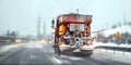 Orange highway maintenance gritter truck spreading de icing salt on road. Dangerous driving conditions