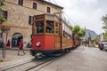 Orange historic tram on rail tracks by buildings against sky in city