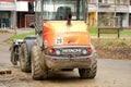 orange Hitachi tractor stands in front of multi-storey residential building, concept of repairing territory, Frankfurt - March