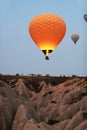 Orange Hot Air Balloon Flying In Sky Above Rocks In Nature Royalty Free Stock Photo