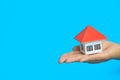 The orange house in human hands on blue background, Real estate concept, Mortgage property home concept, Copy space