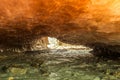 Orange ice cave carved into the Vallelunga glacier crossed by a stream Royalty Free Stock Photo