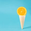 Orange in ice cream cone. Summer coming design idea. Aesthetic refreshment on a sky blue background. Fruity ice cream